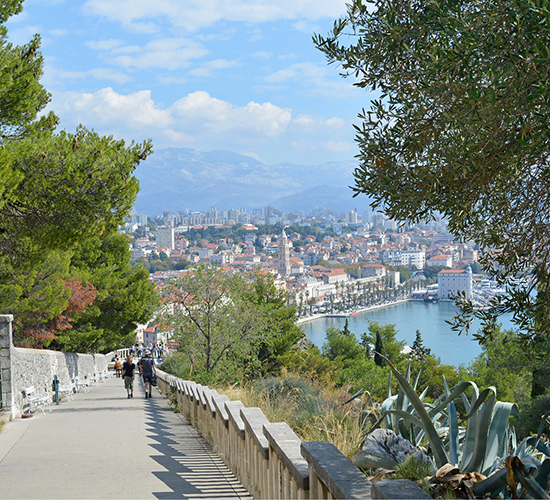 Strollers on a coastal path with mountains in the background in Croatia.