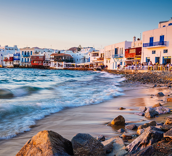 Waves crashing onto the beach in a coastal town in Greece.