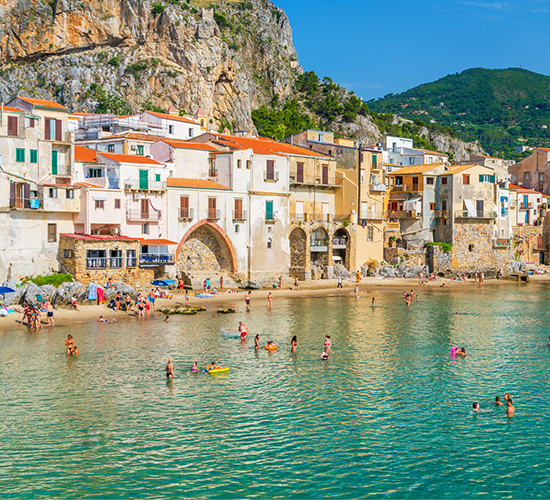 Swimmers enjoying a beautiful beach in a seaside village in Italy.
