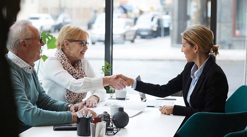 Couple booking a trip in a travel agents office with city traffic outside