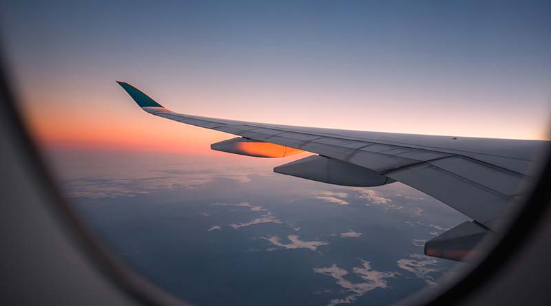 Sunrise haze over airplane wing seen through window