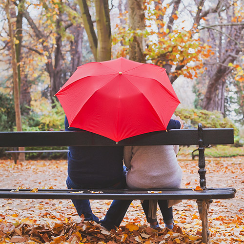 Couple sitting under a red umbrella